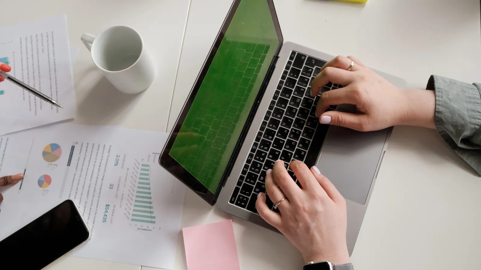 Staf payroll membandingkan slip gaji bulanan dengan data di laptop saat menghitung PPh 21 karyawan