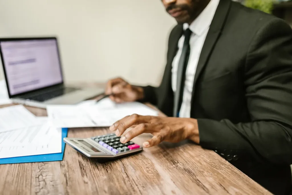 Staf HR menghitung gaji karyawan dengan kalkulator dan dokumen payroll di kantor
