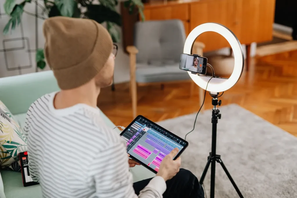 Kreator konten merekam dan menyunting video di studio rumah dengan lampu ring dan tablet