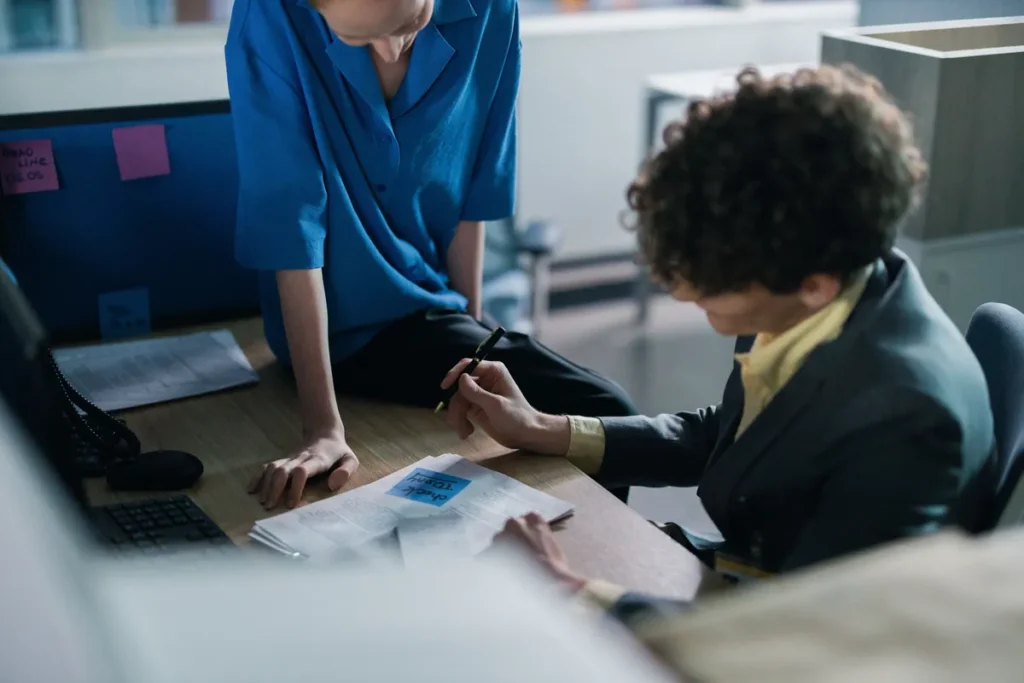 Dua staf memeriksa dokumen tagihan pengadaan di meja kantor instansi